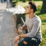 Jeune homme fumant cigarettes électroniques