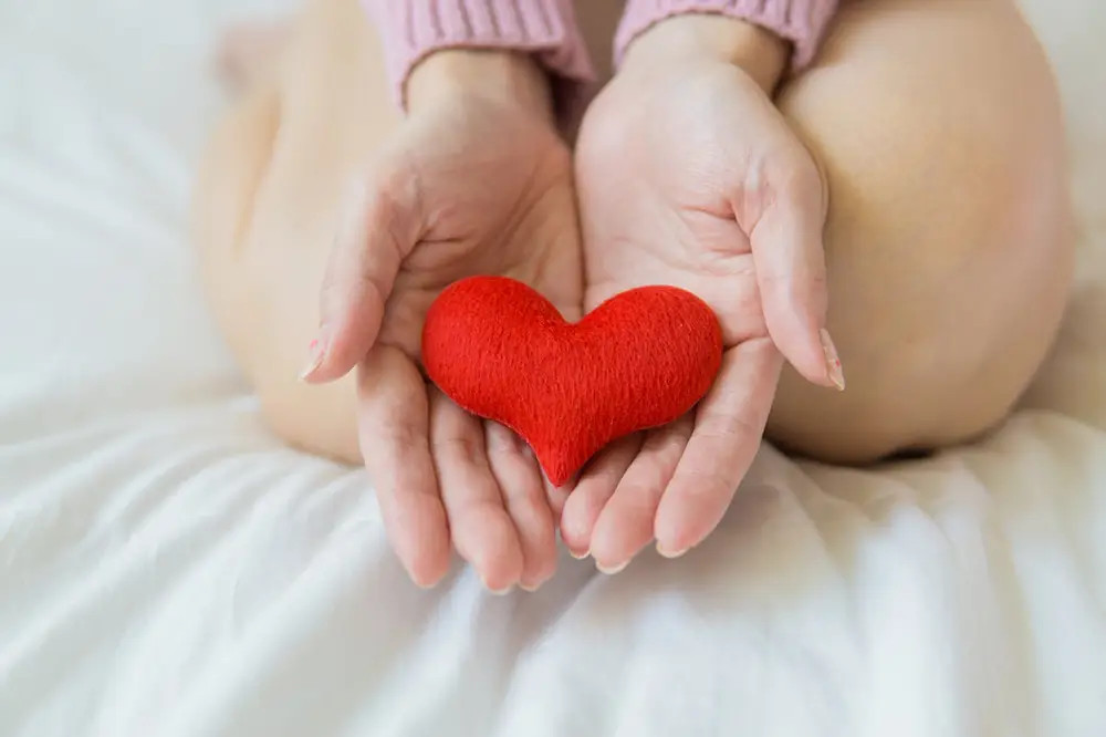 personne qui tient un cœur rouge dans ses mains