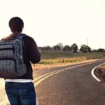 voyageur marchant au bord de la route avec un sac a dos