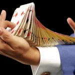 Magicien avec des cartes dans les mains et sur son bras, faisant un tour de magie