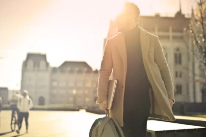 homme d'affaire portant un manteau tendance et marchant avec le soleil dans le dos