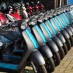 une multitude de motos électriques alignés et garés sur une rue, devant un magasin