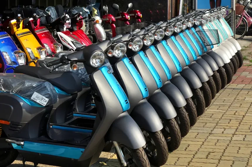 une multitude de motos électriques alignés et garés sur une rue, devant un magasin