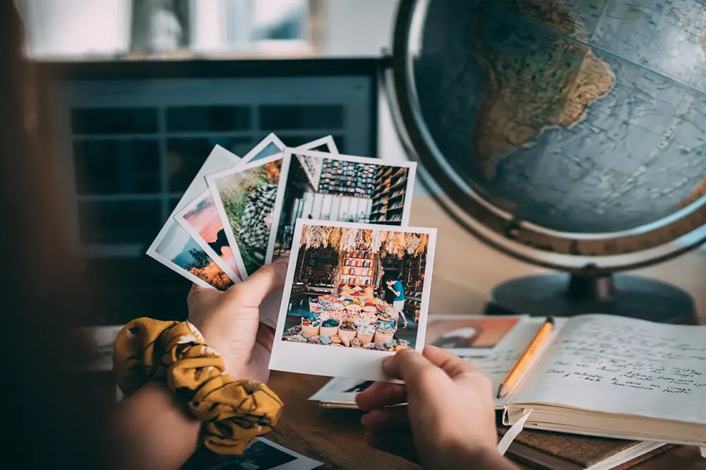 regarder des photos souvenir de voyage avec mélancolie devant un globe terrestre