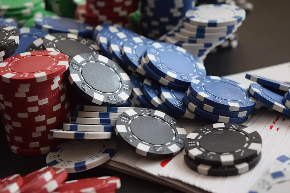 Jetons de casinos en ligne de différentes couleurs noirs, rouges, bleus, blancs