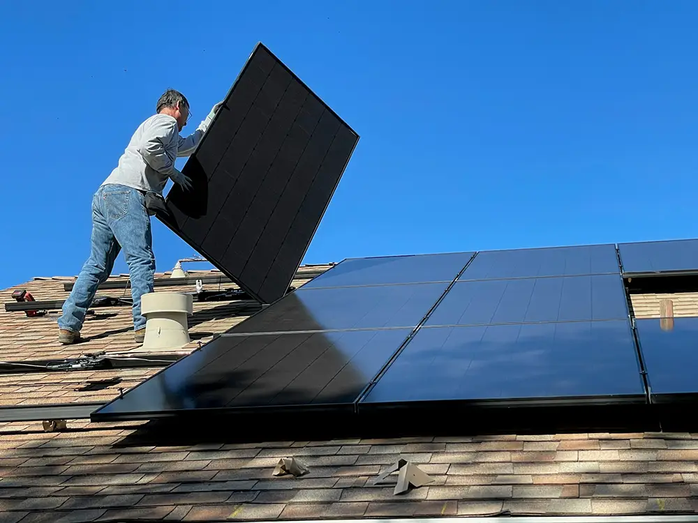 installateur de panneaux solaires qui travaille sur un toit incliné d'une maison
