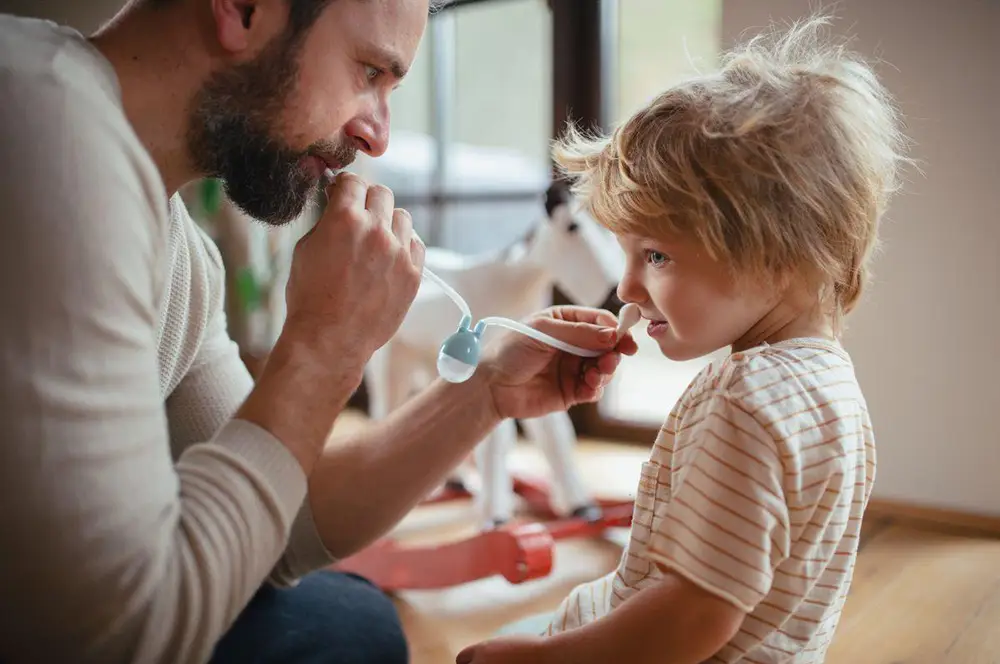 papa utilisant un mouche bébé avec son enfant