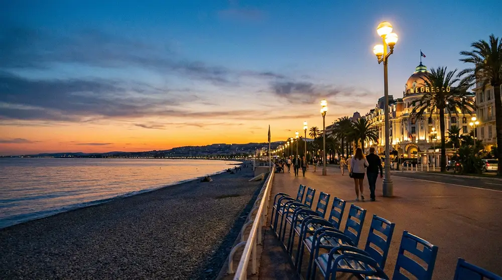 Promenade des Anglais à Nice éclairée au crépuscule avec les chaises bleues au premier plan