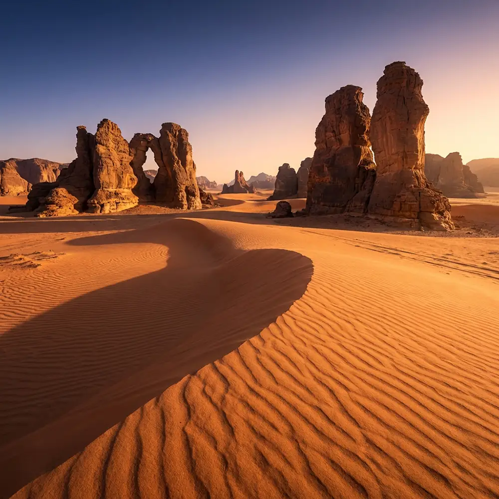 Dunes orange et formations rocheuses du Tassili N'Ajjer dans le Sahara algérien au lever du soleil