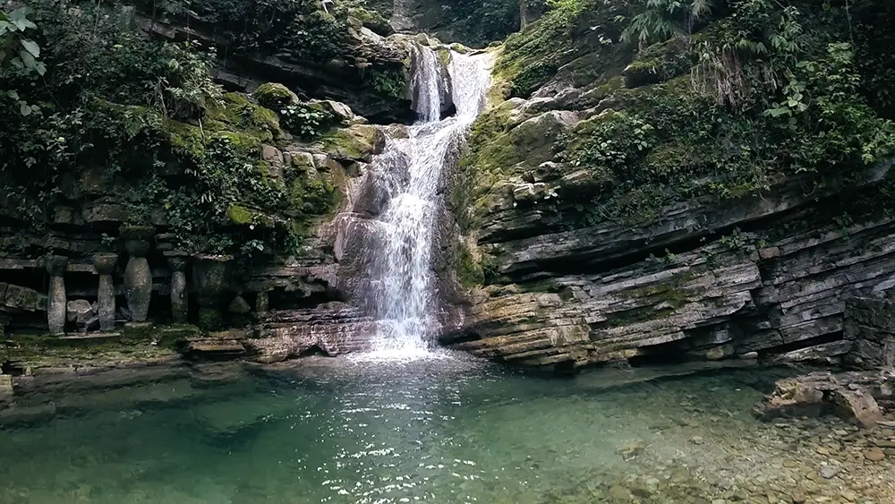 Cascade et bassin d'eau cristalline aux abords du jardin surréaliste Las Pozas à Xilitla, entourés de rochers couverts de mousse et de végétation tropicale