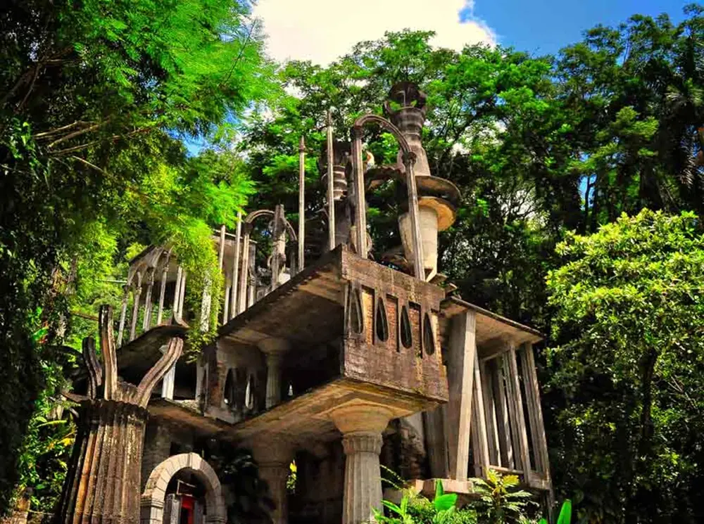 Structure architecturale surréaliste en béton à plusieurs niveaux avec arches gothiques et colonnes envahies par la végétation tropicale à Las Pozas, Xilitla, Mexique