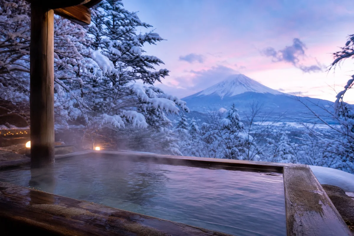 Onsen japonais en plein air - bain thermal rituel Bain thermal japonais onsen en plein air avec vue sur montagne enneigée et vapeur