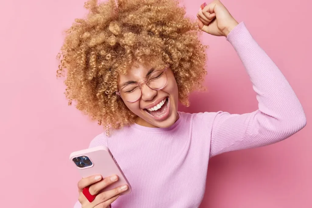 Jeune femme avec son smartphone, heureuse d'avoir téléchargé une application sans problemes