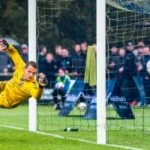 Ballon de football entrant dans le but avec gardien qui plonge. Sport streaming