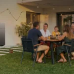Batterie maison modulaire fixée au mur d'une maison pendant un dîner en famille sur la terrasse le soir